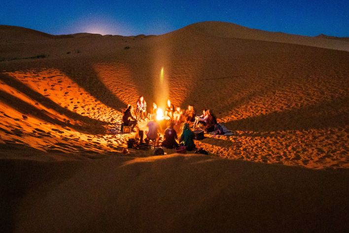 People Sitting in Front of Bonfire in Desert during Nighttime